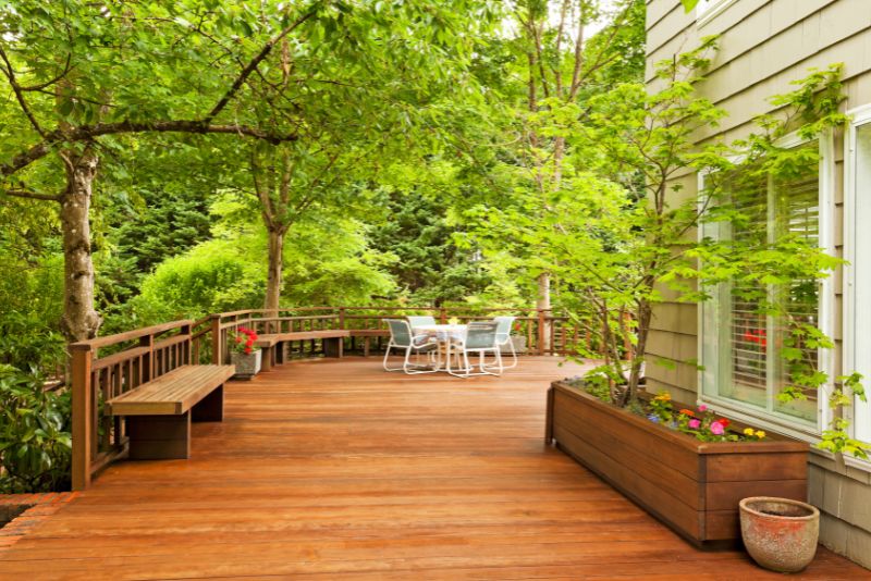 spacious timber deck with trees all round and potted flowers
